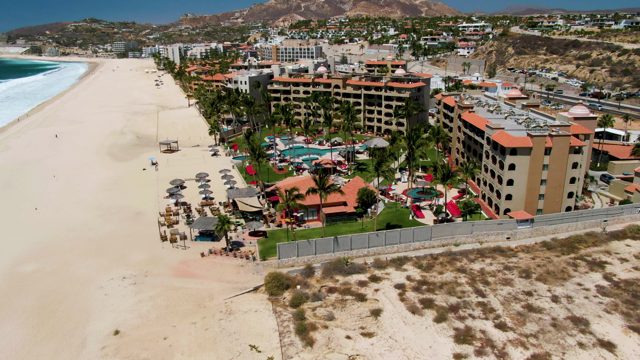 Beachgoers Walking Along Sandy Shore near Resort