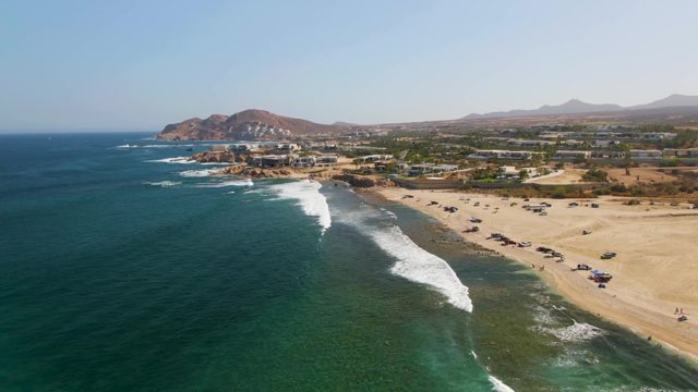 Waves Rolling Onto Sandy Shore From Aerial View