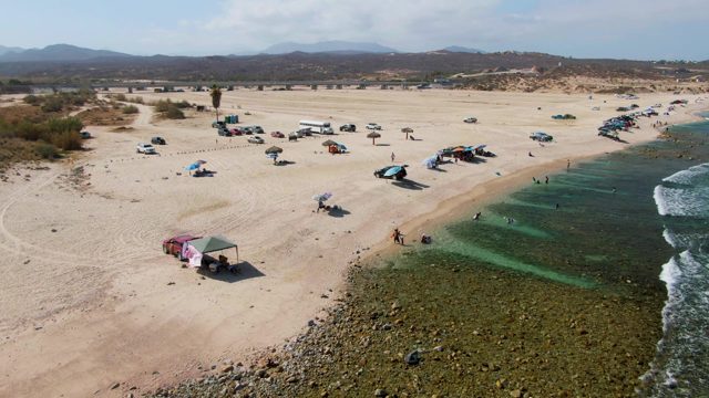 Sandy Beach with People, Vehicles, and Waves