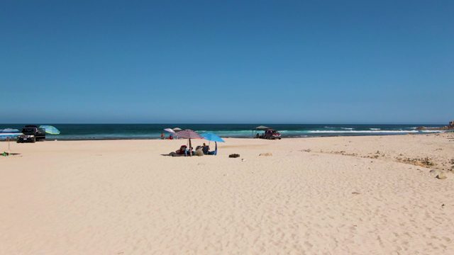 Beachgoers Relaxing Under Umbrellas on Sandy Shore