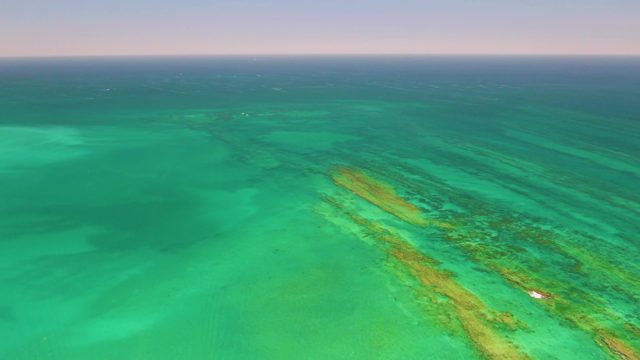 Narrow Reef in Turquoise Ocean with Small Boat Moving
