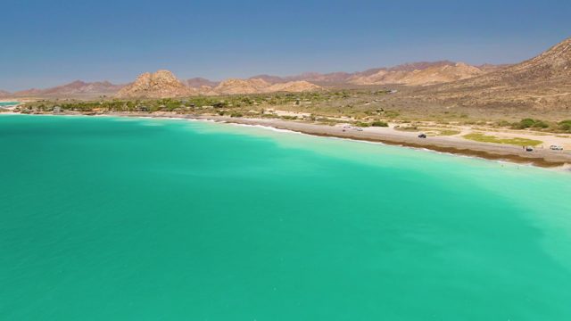 Vehicles Moving Along Coastal Road by Turquoise Waters