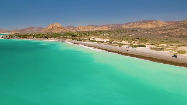 Cars Driving on Beach Road Beside Turquoise Water