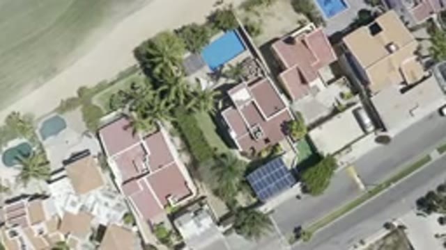 LOS CABOS MEXICO-2019: White Car Moving on City Road Past Houses and Parked Vehicles