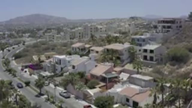 LOS CABOS MEXICO-2019: Descending Shot of Dwellings Set on Hillsides with Road and Palm Trees