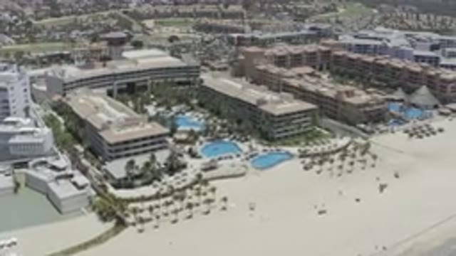 LOS CABOS MEXICO-2019: Camera Pans Over A Beachside Resort In The Sun With Pools And Palm Trees