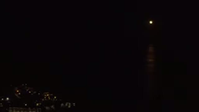 LOS CABOS MEXICO-2019: Camera Pans From Small Distant Moon To Lighted City At Night