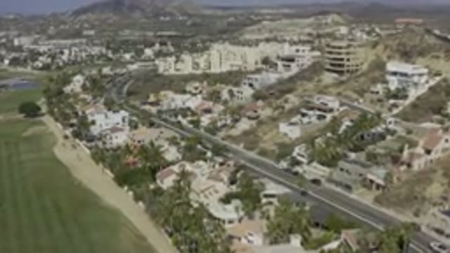 LOS CABOS MEXICO-2019: A Street With A Car Passing On The Left An Open Field And