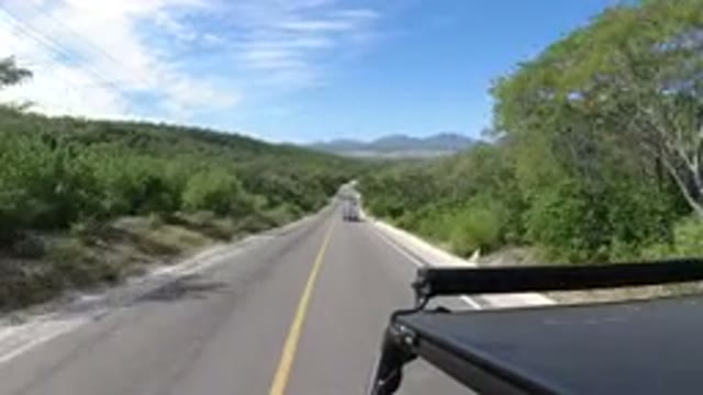 LOS CABOS MEXICO-2019: Car Cruising Down Road Surrounded By Brush With Other Car