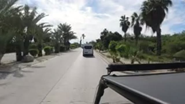 LOS CABOS MEXICO-2019: Car Driving on a Sunlit Street with Buildings and Landmarks