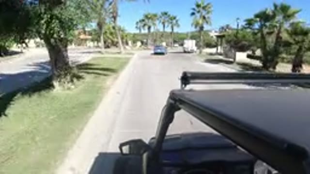 LOS CABOS MEXICO-2019: Blue Car and White Truck Driving Through Traffic and Turning onto Driveway