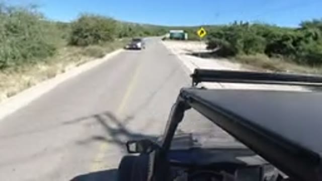 LOS CABOS MEXICO-2019: Vehicle Moves Down Winding Road with Street Signs and Cacti