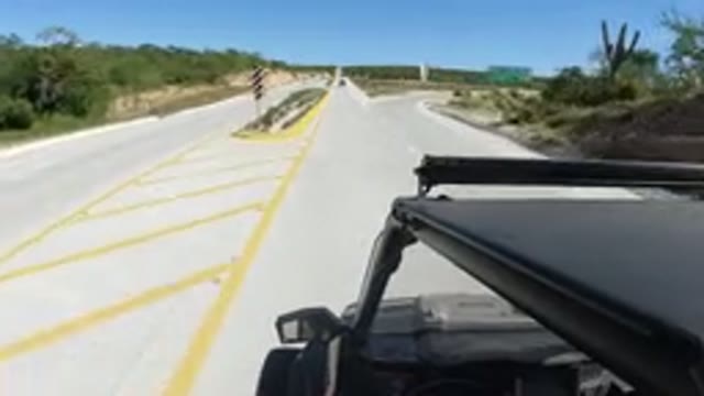 LOS CABOS MEXICO-2019: Car Speeding Down Road While Driver Enjoys Beautiful Scenery