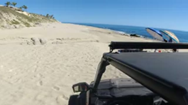 LOS CABOS MEXICO-2019: Black Car Parked On Sandy Beach While Driver Enjoys Nice Weather