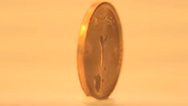 Gold Coin Slowly Spinning With Arabic Numbers On A Cream White Background