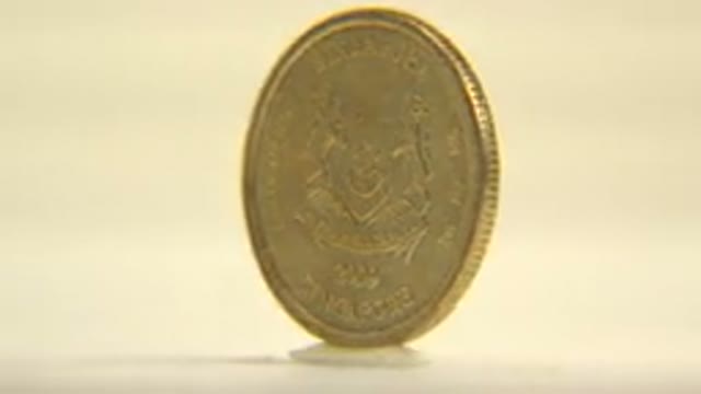 View Of A Five Cent Coin Rotating Around Its Vertical Axis On A White Surface