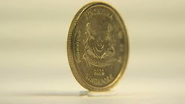 Gold Plated Singapore Coin Slowly Rotates On Ground With Mesmerizing Spins