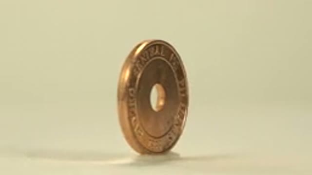 A Five Dollar Coin With A Hole Drilled In The Middle Rolling