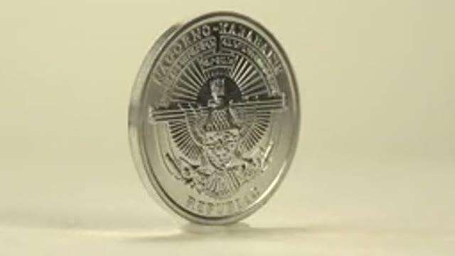 A Silver Coin Is Rotating That Has A Man On One Side And An Object On The Other