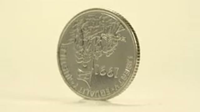 Rotating Silver Coin On White Surface With Writing On One Side And A Bird On The