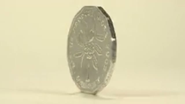 A Shiny Silver Jamaican Coin Rotating In Circular Motion On A White Table