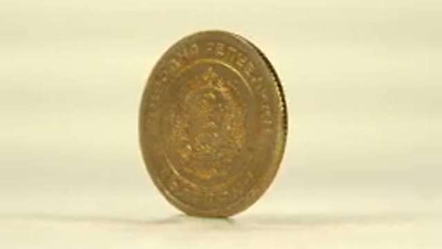 A Gold Colored Coin Standing On Its Side Rotating Around To Show Both Sides