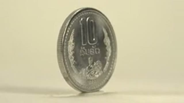 A 10R Coin Rotating On A Silver Plate