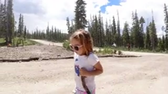 WINTER PARK COLORADO-2019: A Little Girl In Sunglasses Walking Along A Large Dirt Path