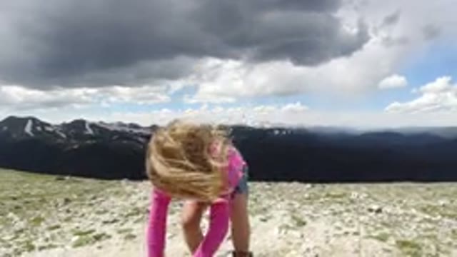 WINTER PARK COLORADO-2019: Blond Girl in Pink Shirt and Denim Shorts Playing on Rocks