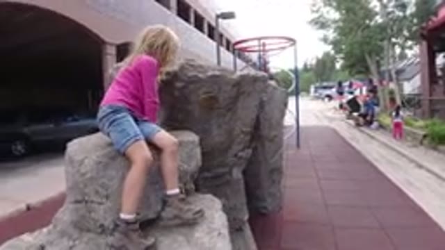 WINTER PARK COLORADO-2019: Little Girl Sitting On A Boulder In A Playground Next