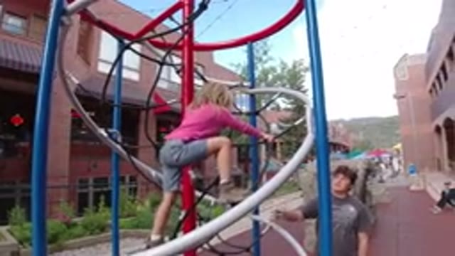 WINTER PARK COLORADO-2019: A Small Blonde Girl Climbing Playground Equipment