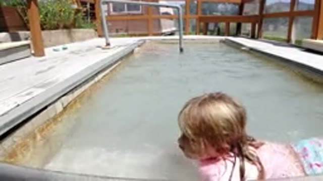 WINTER PARK COLORADO-2019: Girl Playing in Kids Pool at Home Surrounded by Wooden Fence