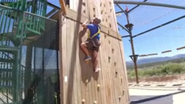 WINTER PARK COLORADO-2019: Man In Blue Shirt Wearing Harness Climbing Wooden Structure