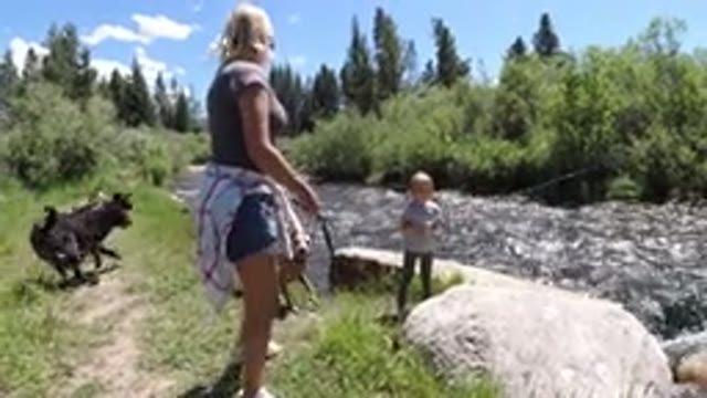 WINTER PARK COLORADO-2019: A Little Girl Fishes In A River While Her Mom Throws A Stick