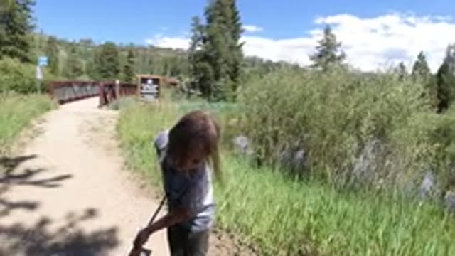 WINTER PARK COLORADO-2019: A Little Girl Playing With a Stick Near a Bridge