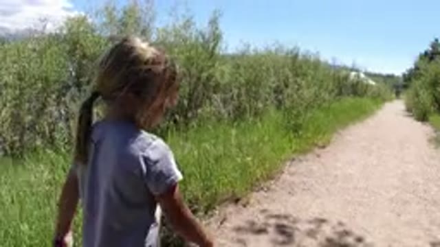 WINTER PARK COLORADO-2019: Little Girl Walking Down A Path With A Long Big Stick