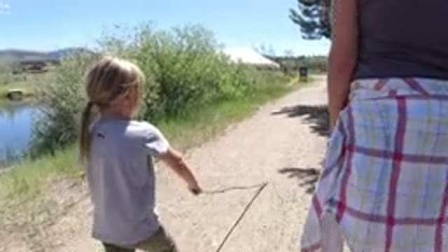WINTER PARK COLORADO-2019: A Small Child Playing With A Branch Accompanied By A