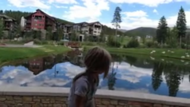 WINTER PARK COLORADO-2019: A Girl Looking at a Pond with Buildings in Background