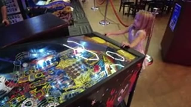 BROOMFIELD COLORADO-2019: Little Girl Playing Pinball in an Arcade Room