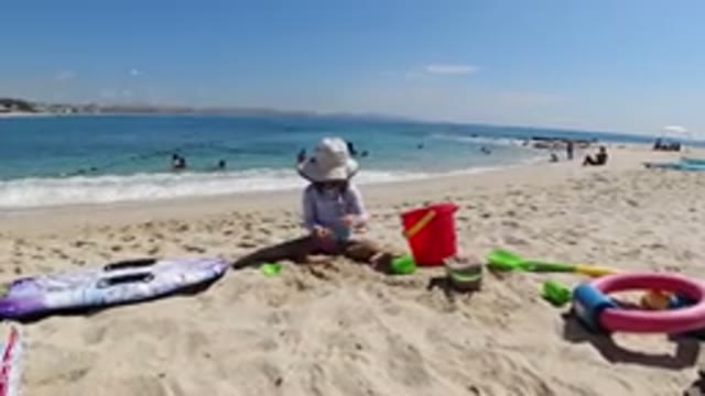 LOS CABOS MEXICO-2019: Kid Playing on Beach Building Sand Castle with Few People
