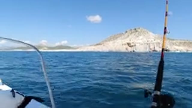 LOS CABOS MEXICO-2019: Boat Gliding Across Calm Waters With Mountain Backdrop