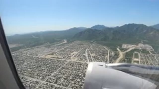 LOS CABOS MEXICO-2019: Plane Flying Over City Overlooked By A Large Mountain