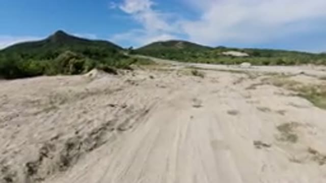 LOS CABOS MEXICO-2019: Vehicle Moves Along Dirt Path Towards Paved Road Green