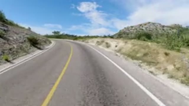 LOS CABOS MEXICO-2019: Road Curve Mountain Hot Summer Sign Clouds Drive Yellow