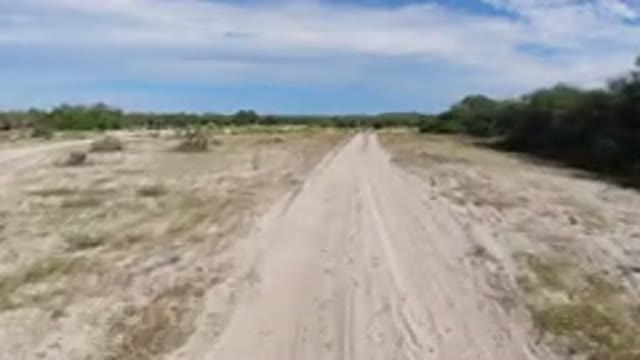 LOS CABOS MEXICO-2019: Vehicle Moves Down Dirt Path Under Bright Blue Sky With Clouds