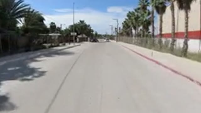 LOS CABOS MEXICO-2019: Vehicle Moves Down City Street Past Buildings Palm Trees