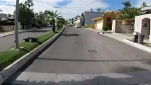 LOS CABOS MEXICO-2019: Vehicle Moves Down Divided City Street Past Buildings