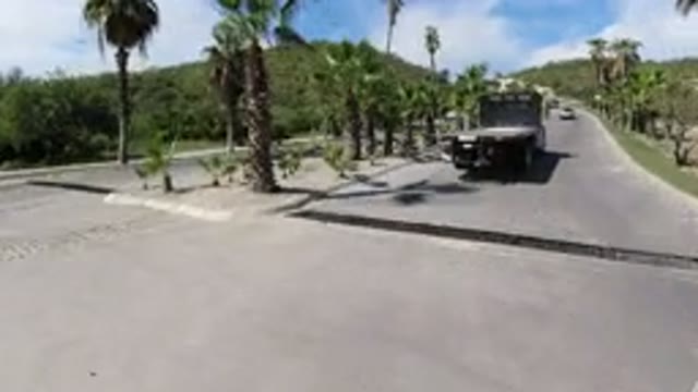 LOS CABOS MEXICO-2019: A Vehicle Turns Behind A Flatbed Truck Onto A Paved Road