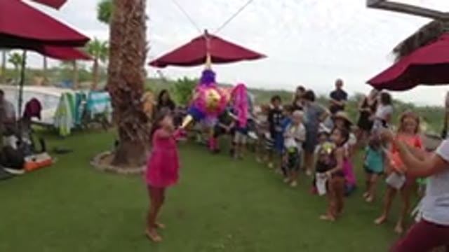 LOS CABOS MEXICO-2019: Girl Hitting Pink Pinata Surrounded By Party Goers