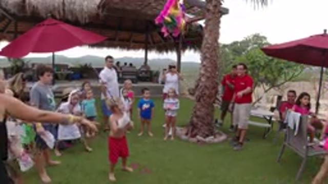 LOS CABOS MEXICO-2019: A Group Of People Crowded Around A Kid Swinging A Stick At A Pinata